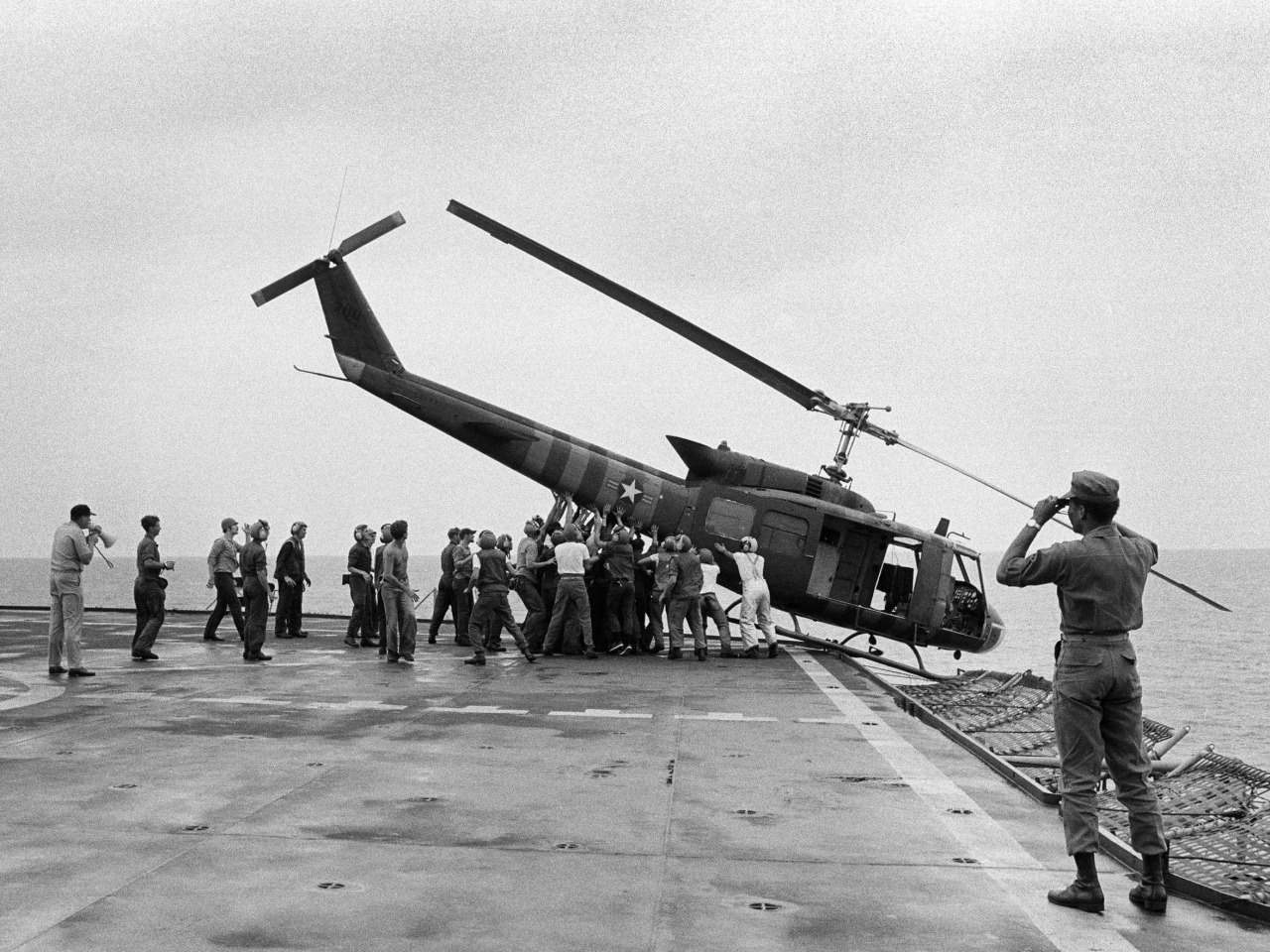 Lính hải quân Mỹ trên chiến hạm USS Blue Ridge đẩy một chiếc trực thăng xuống biển để dọn chỗ đón những chuyến bay chở người di tản khác từ Sài Gòn tới.