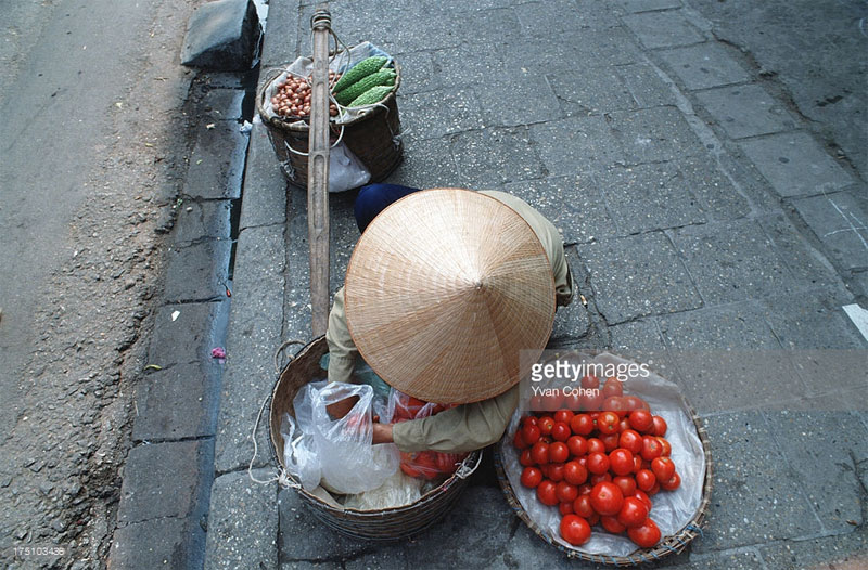 Một người phụ nữ bán rau quả rong bên vỉa hè.