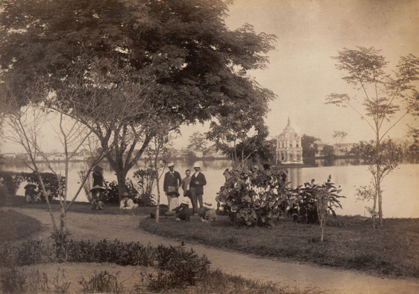 Nhóm quan chức Pháp và các tùy tùng người Việt nghỉ ngơi bên bờ hồ, phía xa là Tháp Rùa