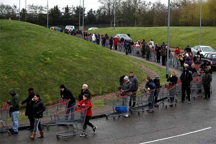 Người dân xếp hàng dài để chờ tới lượt mua sắm bên ngoài một cửa hàng ở Watford, Anh