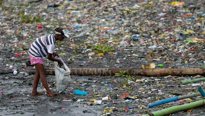 Một người phụ nữ nhặt những chiếc cốc nhựa dọc theo bờ sông Pasig đầy rác thải ở Manila