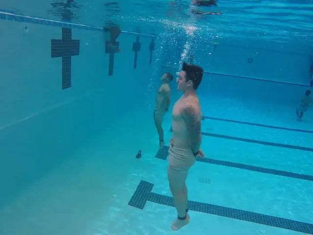 Một học viên đang thực hiện bài bơi dưới nước trong khi bị trói tay và chân.