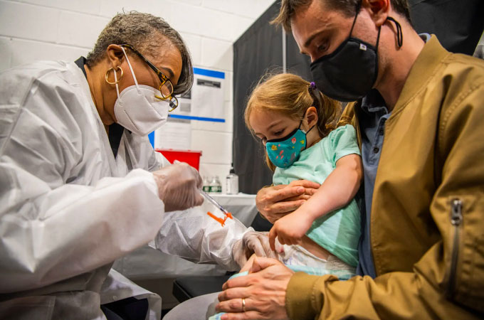 Một bé gái hai tuổi được tiêm vaccine Moderna vào chân tại Quảng trường Thời đại ở Mỹ