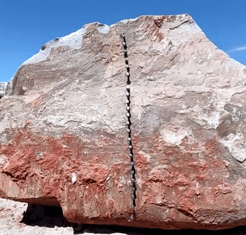 Ahmet Pehlivanoglu dùng búa đóng đinh kim loại vào một vết nứt ở giữa bề mặt của tảng đá.