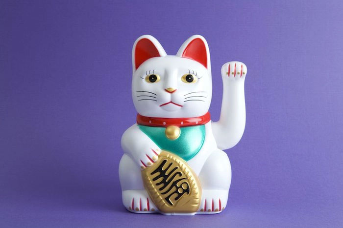 Maneki-neko mô tả một con mèo Bobtail Nhật Bản đang giơ chân ra hiệu mời chào.