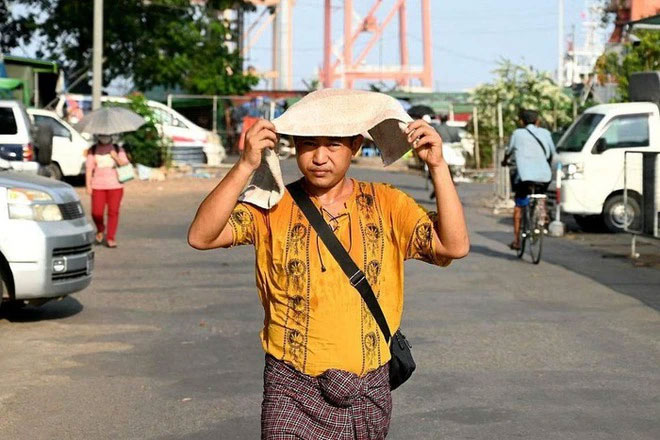 Một người đàn ông trùm khăn lên đầu để tránh nắng trong đợt nắng nóng ở Yangon