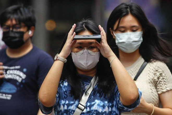  Người phụ nữ lấy điện thoại che mặt trong một ngày nắng nóng ở Kuala Lumpur